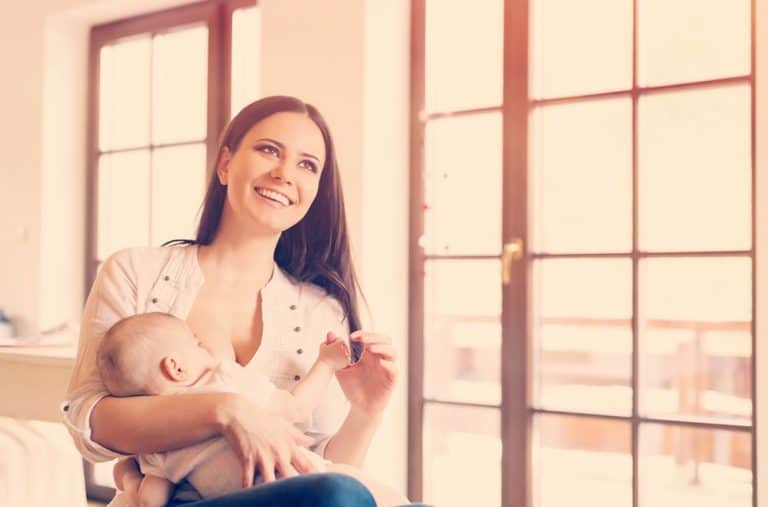 Mujer sonriente con su bebé al pecho
